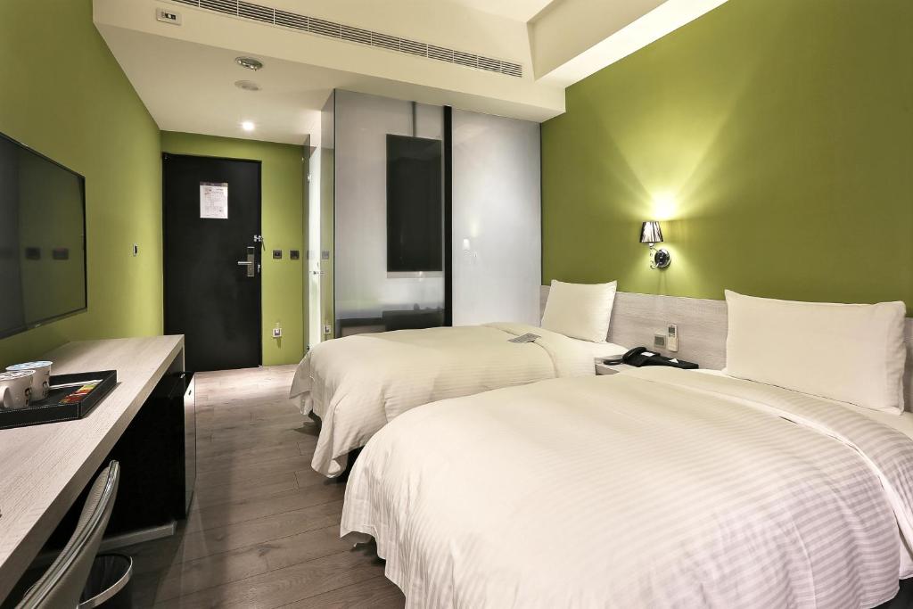 two beds in a hotel room with green walls at Miller Inn in Taichung