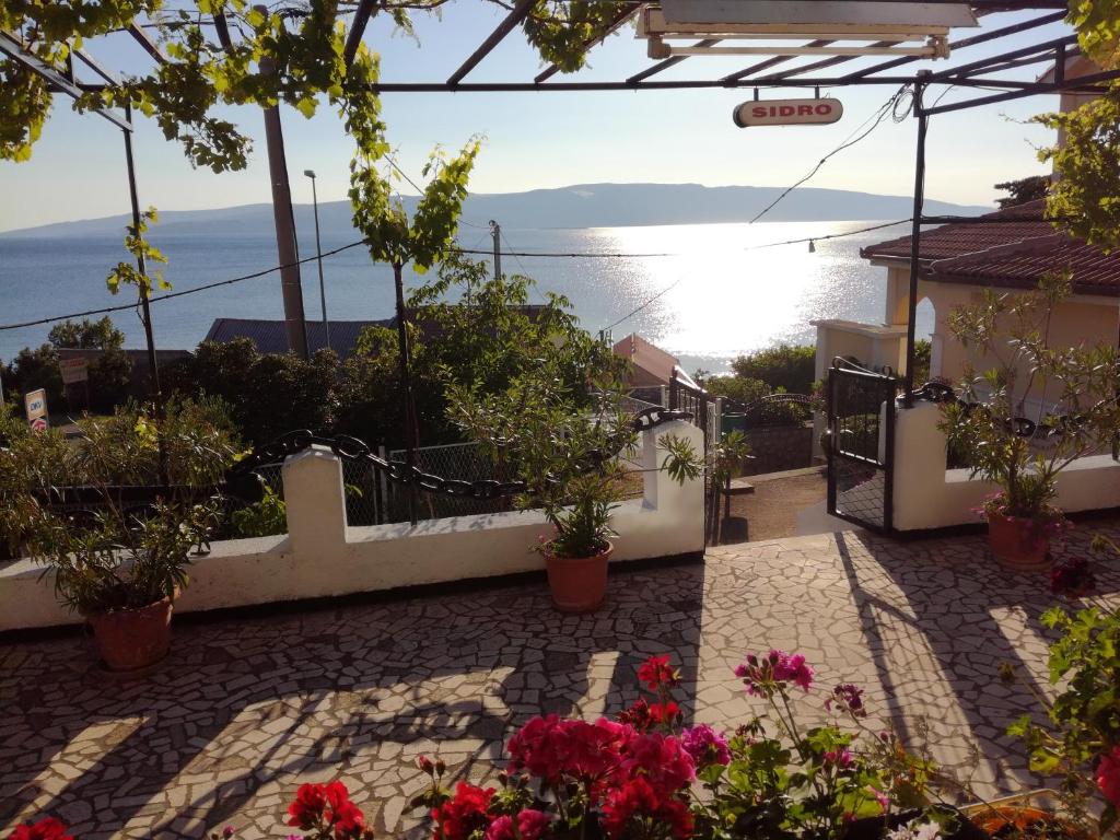 a patio with flowers and a view of the ocean at Apartmani Sidro Senj in Senj