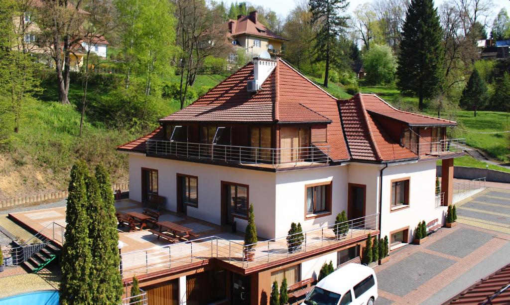 Two-story guesthouse with red tile roof, balconies, terraces and parked white van.