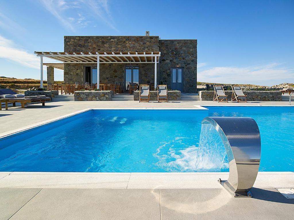 a swimming pool in front of a house at Lithos Luxury Rooms (Adults Only) in Adamantas