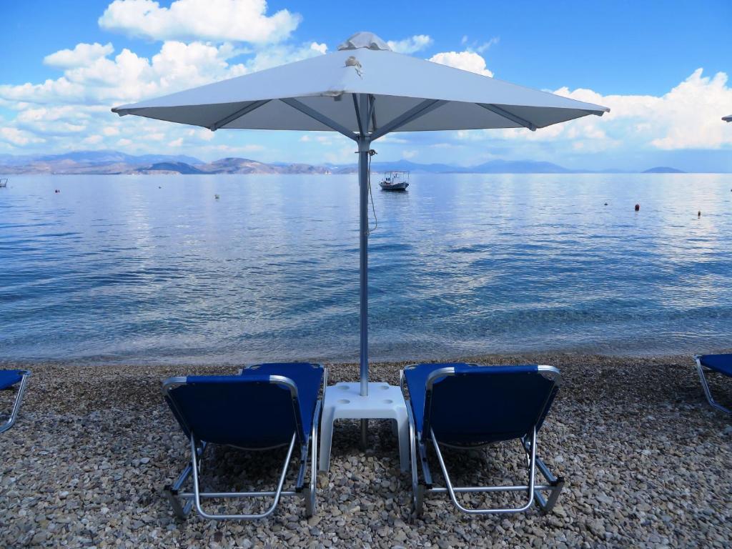 twee stoelen en een parasol op het strand bij Blue Sky Apartments & Rooms in Xiropigado