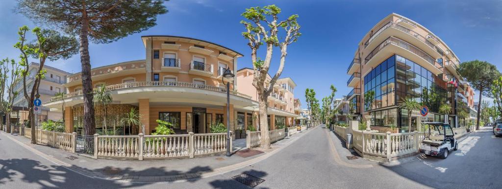 un bâtiment situé dans une rue bordée de palmiers. dans l'établissement Hotel Mediterraneo Club Benessere, à Bellaria-Igea Marina