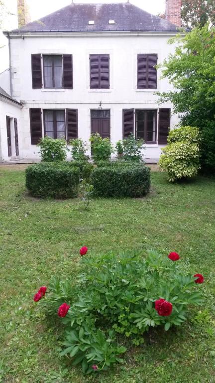 una casa blanca con flores rojas en el patio en VILLA ESPERANZA Suite de 2 à 4 personnes proche Zoo de Beauval et châteaux de La Loire, en Valençay