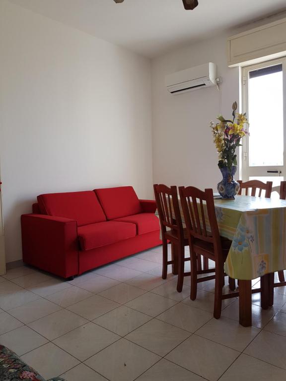 - un canapé rouge dans le salon avec une table et des chaises dans l'établissement Apartment Colaianni, à Torre San Giovanni