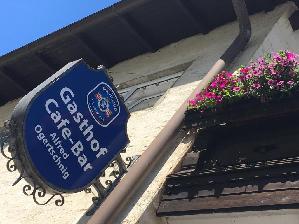 ein blaues Schild an der Seite eines Gebäudes mit Blumen in der Unterkunft Gasthof Ogertschnig in Klagenfurt am Wörthersee