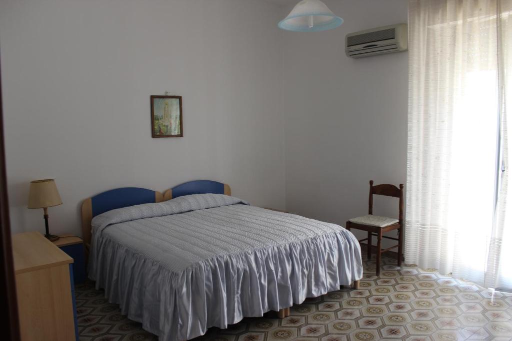 a bedroom with a bed and a chair and a window at B e B CASA DA PINA in Ragusa