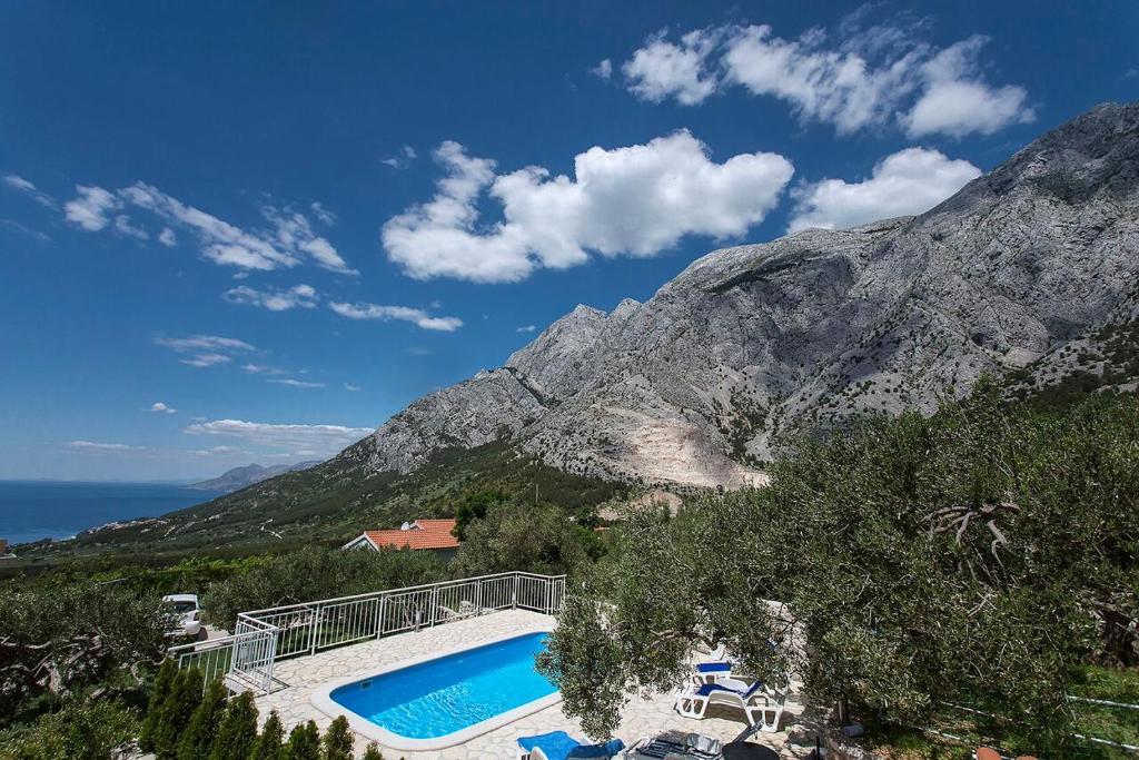 a house with a swimming pool in front of a mountain at Holiday Home Chill Zone in Baška Voda