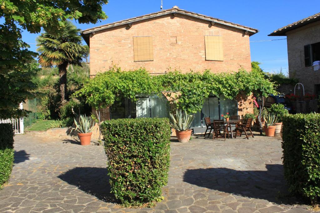 une maison en briques avec des buissons devant elle dans l'établissement Vignano40, à Sienne
