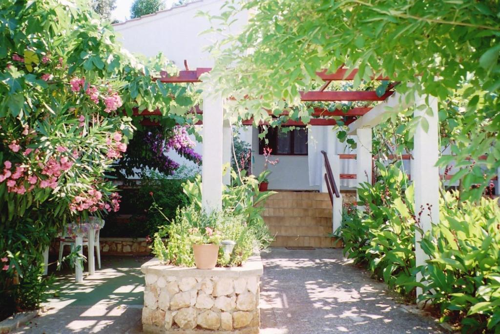 een tuin met een witte pergola en enkele bloemen bij Apartments Lovor in Silba