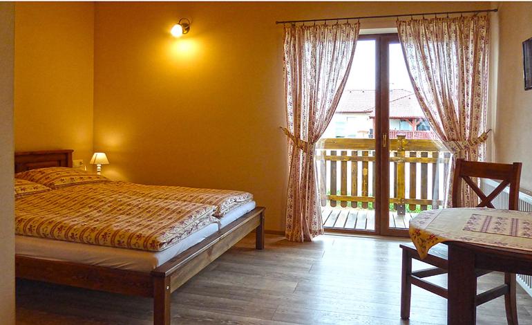 a bedroom with a bed and a window with a balcony at Penzión Thamasy in Spišské Tomášovce