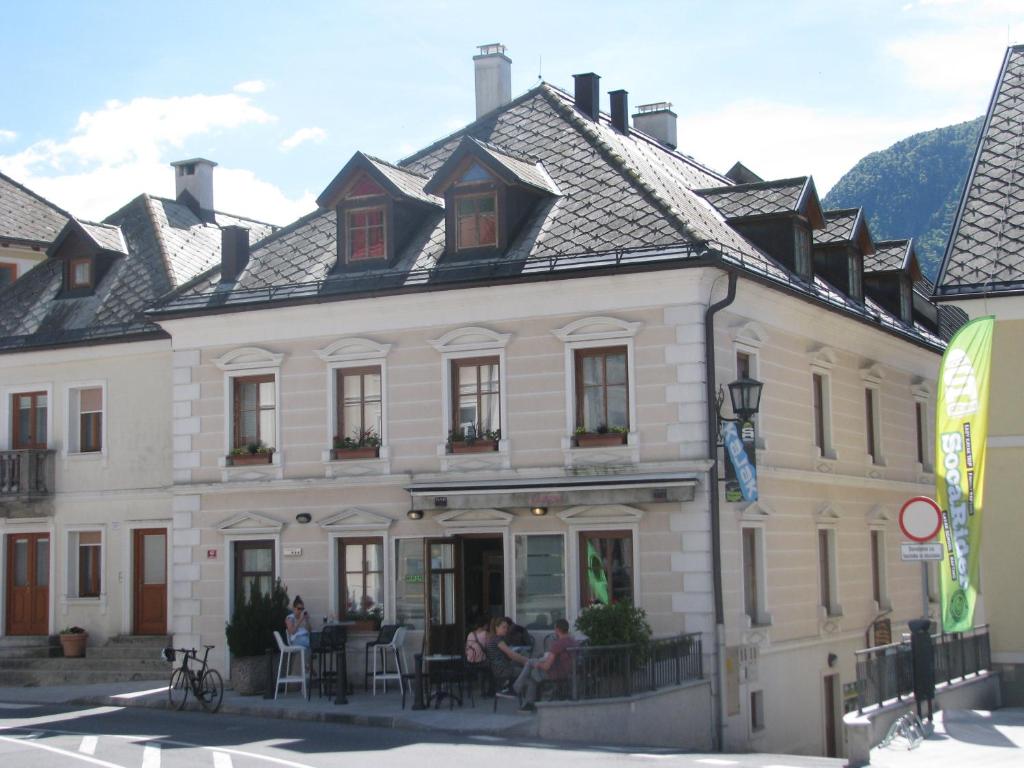 a large white building with people sitting outside of it at Apartment Gaspercic in Bovec