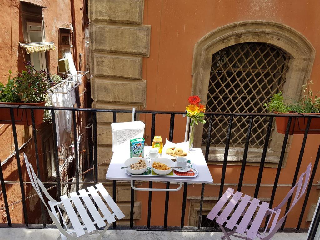 - une table avec de la nourriture sur un balcon avec 2 chaises dans l'établissement SanBiagio, 25 Guesthouse, à Naples