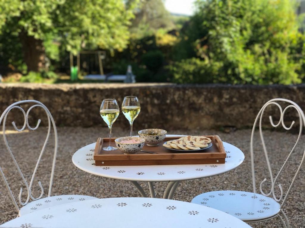 een dienblad met eten en twee glazen wijn op een tafel bij Chai Merlot in Saint-Cyprien