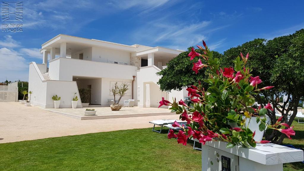 a white house with pink flowers in the yard at Case Vacanza Marzano in Monopoli
