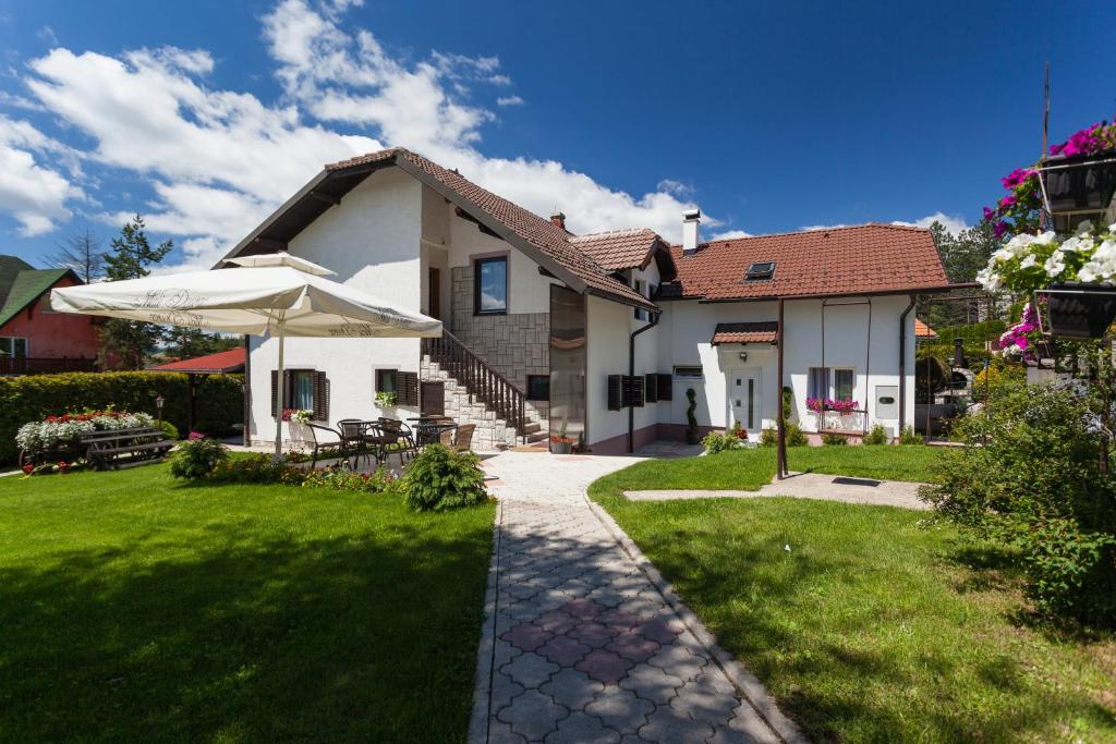 a house with a green lawn and an umbrella at Vila Aleksandra in Zlatibor