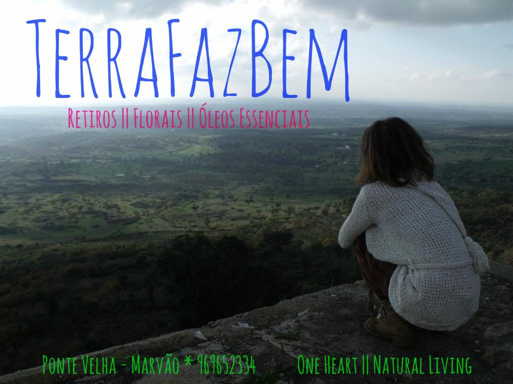 una mujer sentada en la cima de una montaña mirando una vista en TerraFazBem, en Marvão