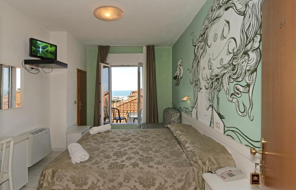 a bedroom with a bed with a painting on the wall at Hotel Regina in Lido di Camaiore
