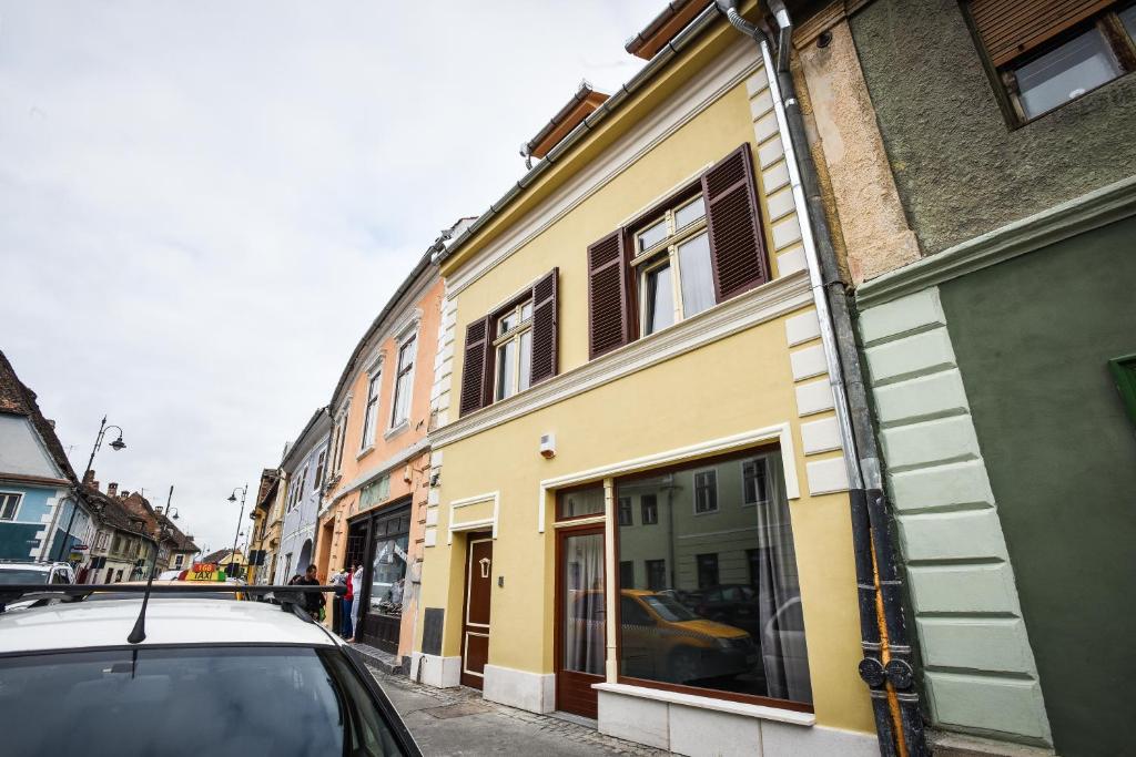 a car parked in front of a yellow building at YellowBoot Aparthotel in Sibiu