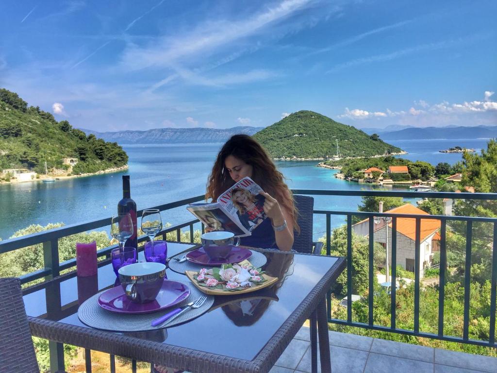 Eine Frau, die an einem Tisch mit einem Teller Essen sitzt. in der Unterkunft Villa Evita Apartments in Prožura