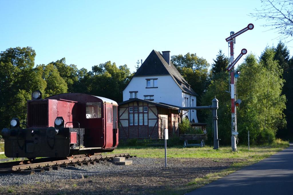 a train car sitting on the tracks in front of a house at "Alter Bahnhof" Schalkenmehren in Schalkenmehren