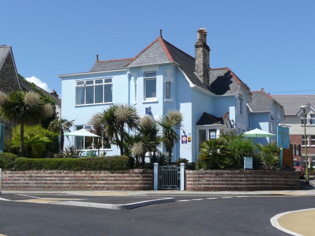 a white house with palm trees in front of a street at Blue Palms in Bournemouth