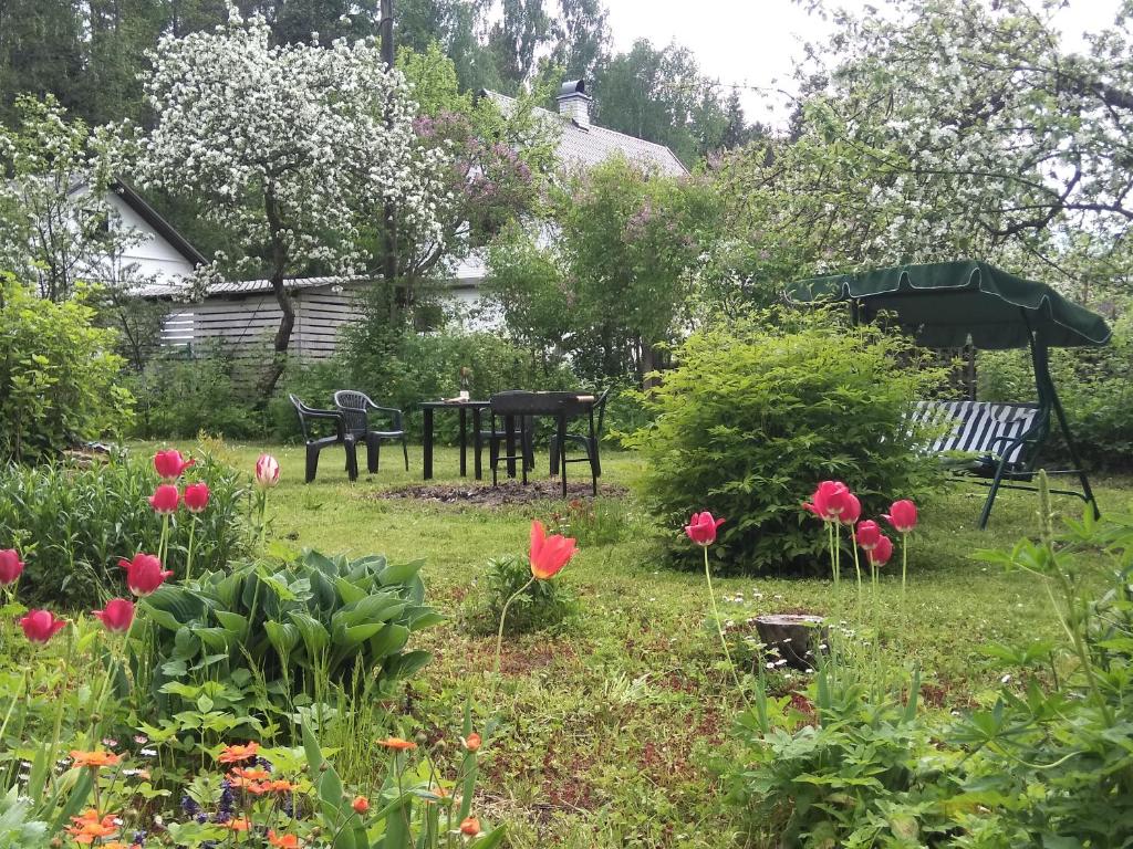 a garden with red flowers and a table and benches at Narva-Jõesuu Apartment in Narva-Jõesuu
