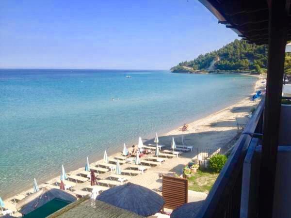 una spiaggia con sedie e ombrelloni e l'oceano di Litsa Apartments a Fourka