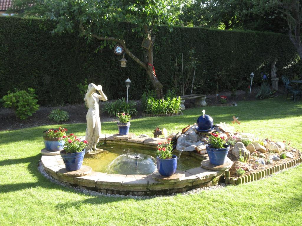 un jardin avec une fontaine et une statue sur l'herbe dans l'établissement Shear Annexe Flat, à Cambridge