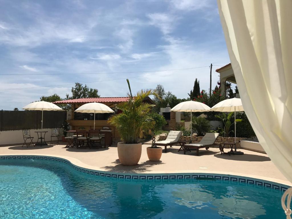 una piscina con sombrillas, mesas y sillas en Cegonha Villa powered by Cegonha Resort- Private swimming pool & air con, en Albufeira