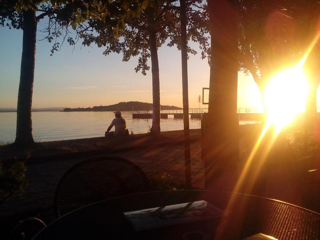 San SavinoにあるGenius Apartmentsの海に腰掛けて夕日を眺める男