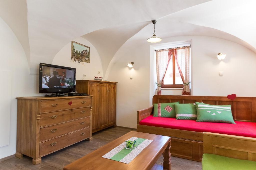 a room with a bed and a tv and a table at Apartments Petacova Hiša in Kranjska Gora
