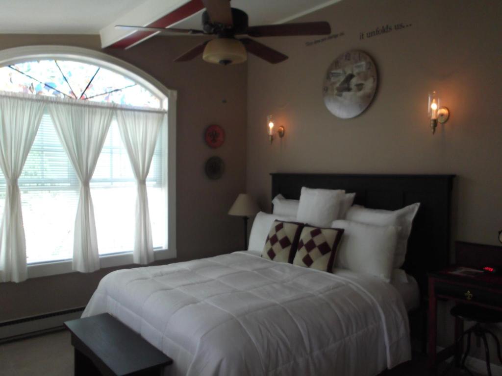 1 dormitorio con cama blanca y ventilador de techo en Changing Times Boutique Country Lodging en West Taghkanic