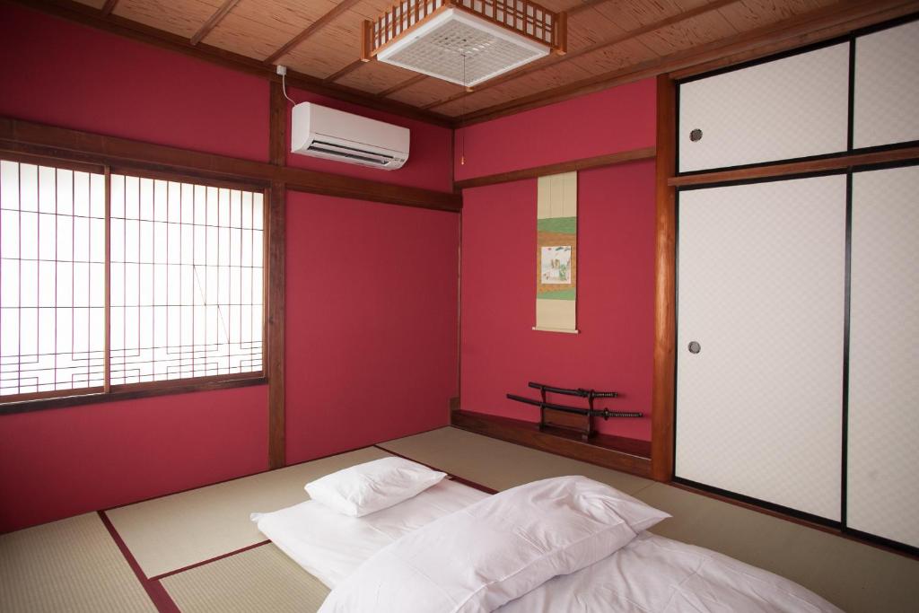 Habitación con 2 camas y pared roja. en Ninja TABI-NE, en Kanazawa