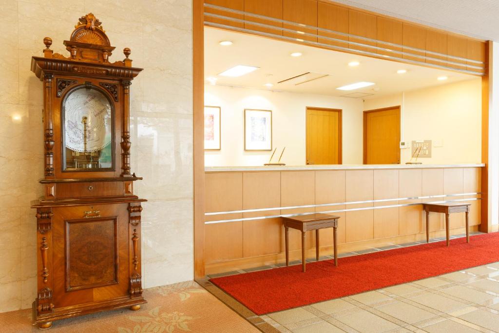 une grande horloge grand-père dans une pièce avec un miroir dans l'établissement Hotel Amabile Maizuru, à Maizuru