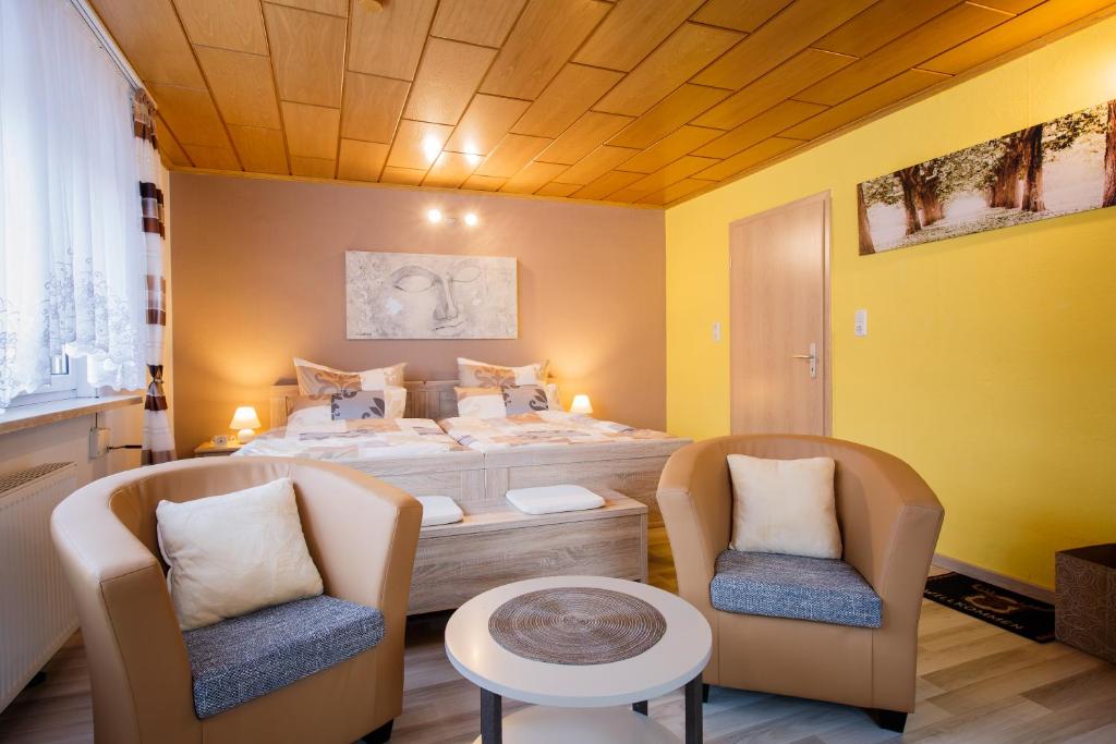 - une chambre avec un lit et deux chaises dans l'établissement Boxis Ferienhaus, à Probstzella