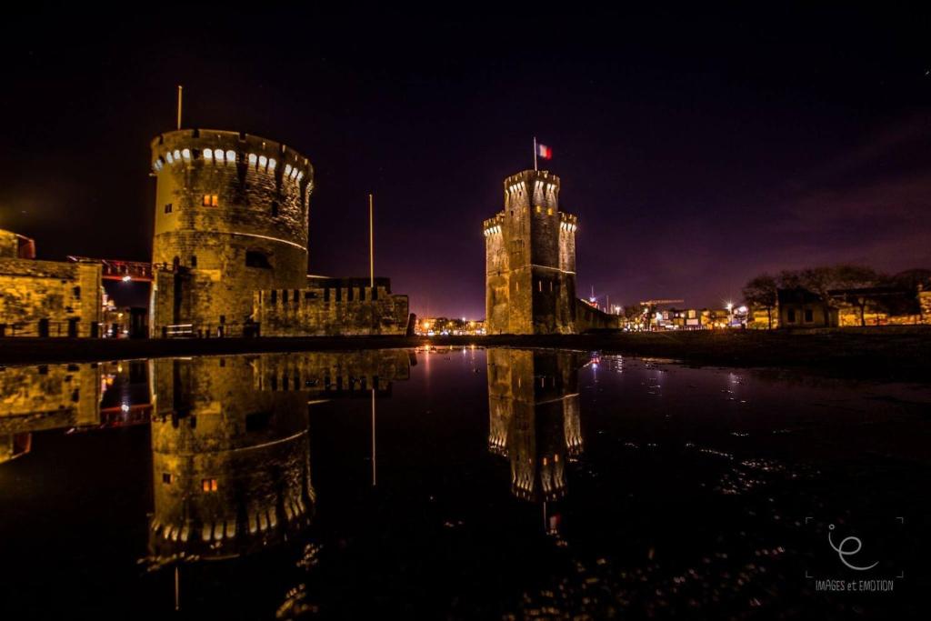 un castillo de noche con su reflejo en el agua en Hôtel Le Rupella, en La Rochelle