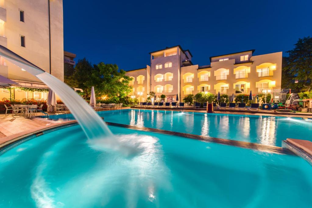 a swimming pool with a fountain in front of a building at Hotel Sport & Residenza in Cesenatico