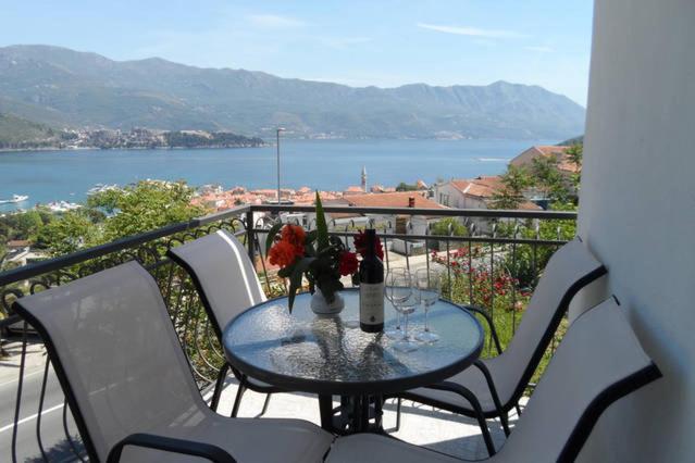 una mesa con un jarrón de flores en el balcón en Guest House Budva, en Budva