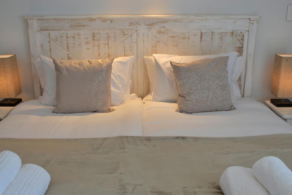 a white bed with white pillows and a headboard at Villa Honeysuckle Luxury 3 Bedroom in Stellenbosch