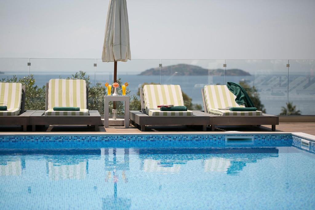 a swimming pool with two lounge chairs and an umbrella at Irida Aegean View, Philian Hotels and Resorts in Megali Ammos