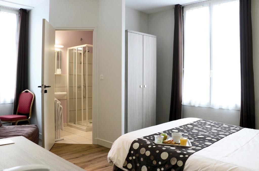 - une chambre d'hôtel avec un lit et un plateau de nourriture dans l'établissement LOGIS -Hotel & Restaurant de la Place, à Aunay-sur-Odon