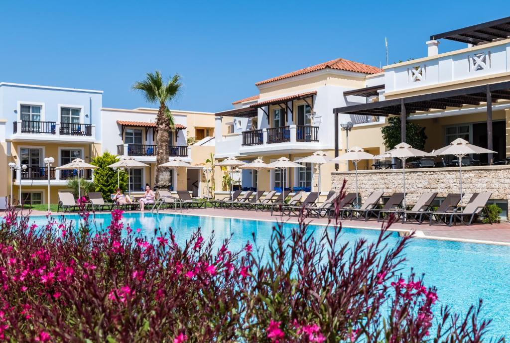 a view of the hotel and the swimming pool with pink flowers at Aegean Houses in Kos