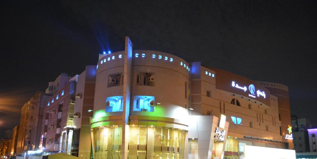 a large building with blue and green lights on it at Rancy Jeddah Aparthotel in Jeddah