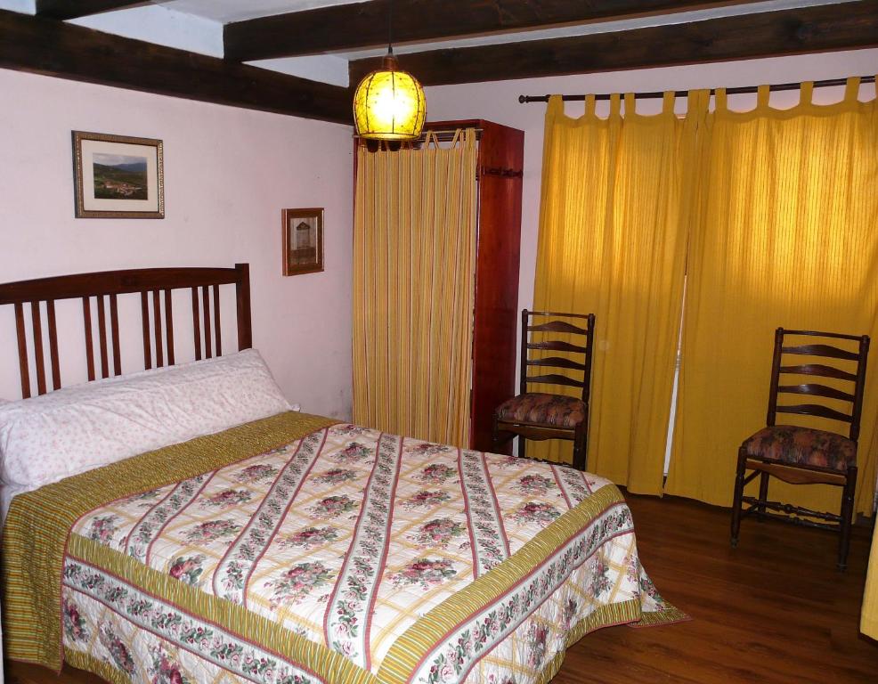 a bedroom with a bed and two chairs at La Colmenita in Navalsaz