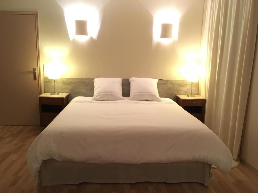 1 dormitorio con 1 cama blanca grande y 2 lámparas en Les Epis d'Or, en LʼIsle-sur-Serein