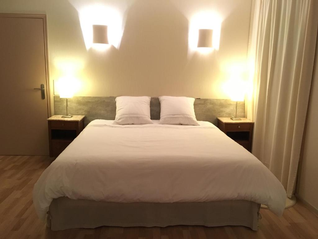 a bedroom with a large white bed with two lamps at Les Epis d'Or in LʼIsle-sur-Serein