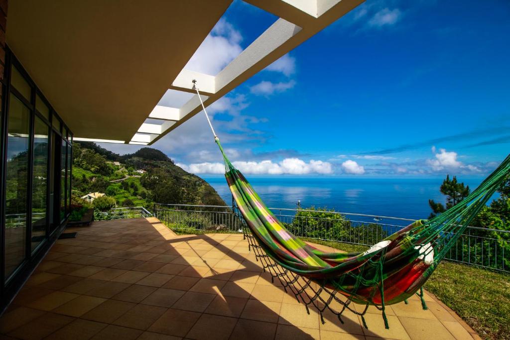 a hammock on a balcony with a view of the ocean at Cottage Ocean View in Porto Moniz
