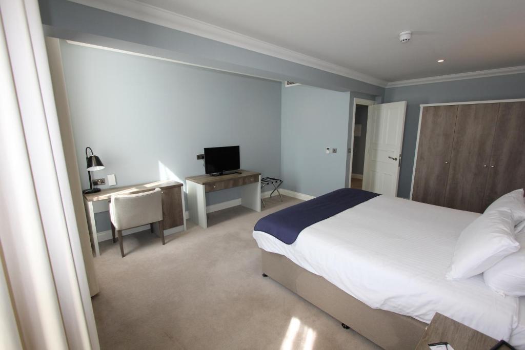 a bedroom with a bed and a desk and a television at Yarrow Hotel in Broadstairs