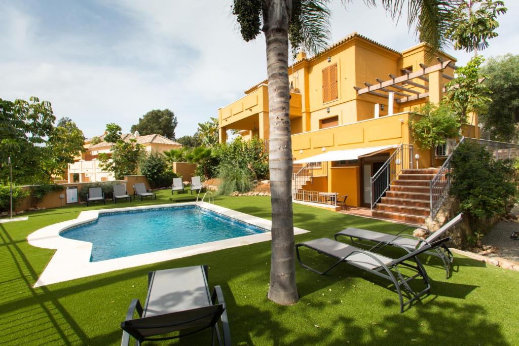 un patio trasero con piscina y una casa en Villa Las Lomas de Marbella en Marbella