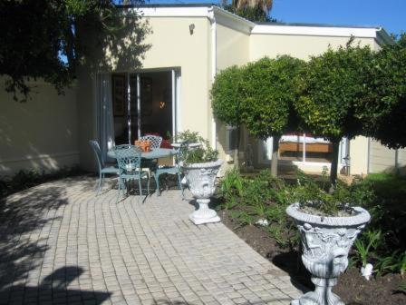 a patio with two urns and a table and chairs at Navona Constantia Guest Cottage in Cape Town